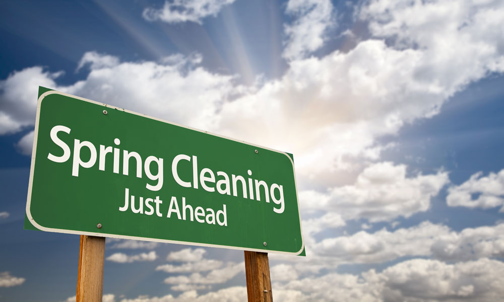 road sign that reads spring cleaning just ahead with cloudy sky in the background