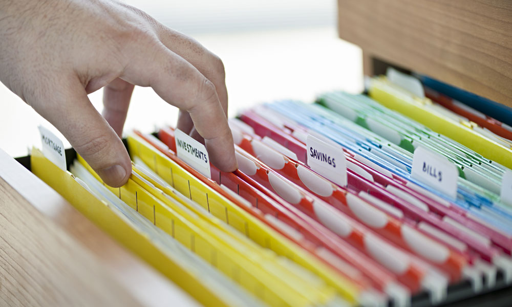 hand sifting through filing cabinet of colour coordinated and labeled folders